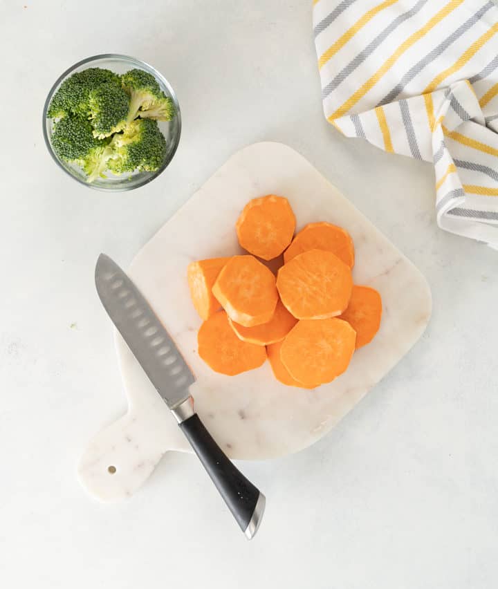Sweet potato medallions and brocolli , knife on a cutting board with kitchen towel 
