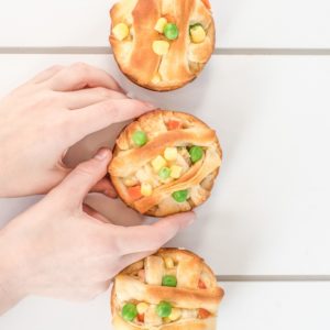 three chicken pot pies with kids hands holding one