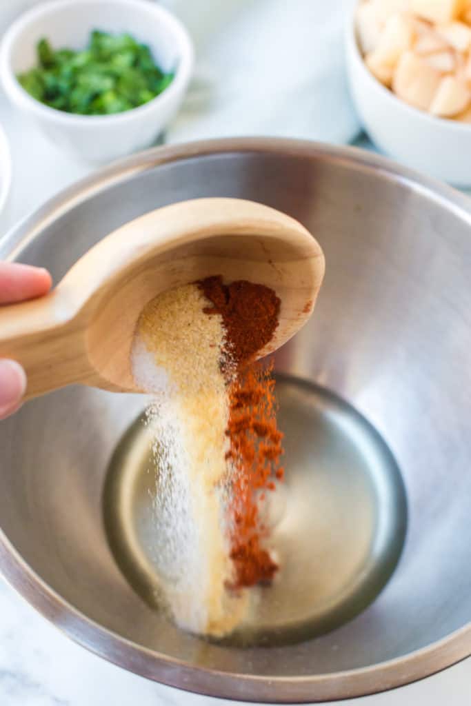 Wooden spoon with spices being poured into a bowl