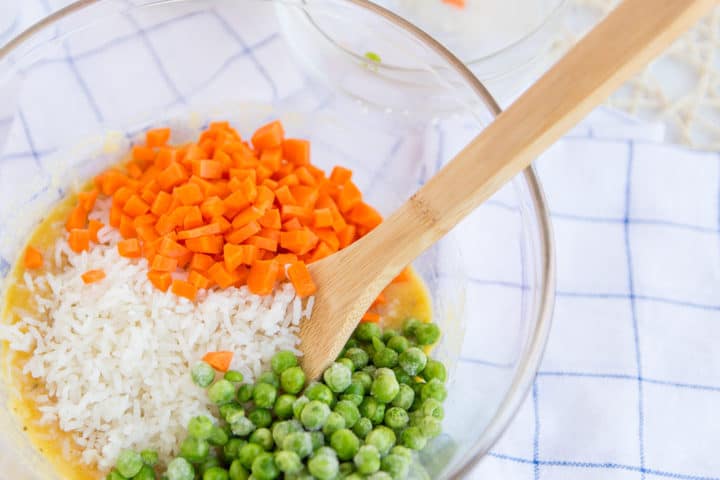 close up of peas, carrots, rice , eggs in a glass dish 