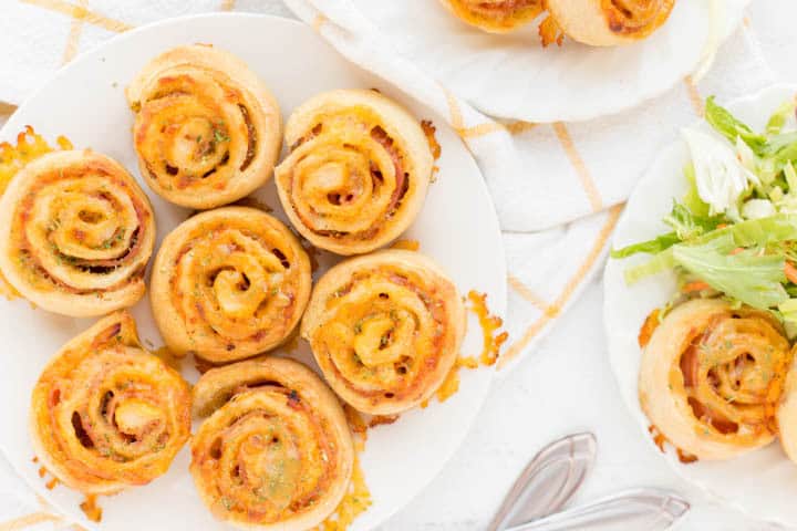 cooked pinwheels with cheese and ham on plate with kitchen towel