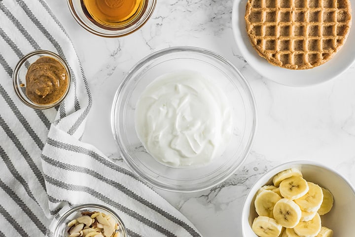 Bowls of ingredients, greek yogurt, banana, honey, and nut butter