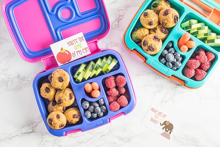 Two lunch boxes filled with muffins, fruit and vegetables