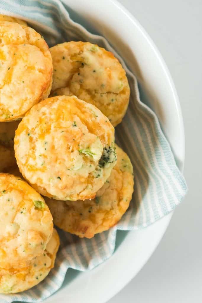 brocolli muffins in a bowl under a striped napkin