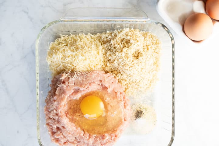 Square glass dish with ground chicken, parmesan cheese, panko breadcrumbs, seasonings and an egg