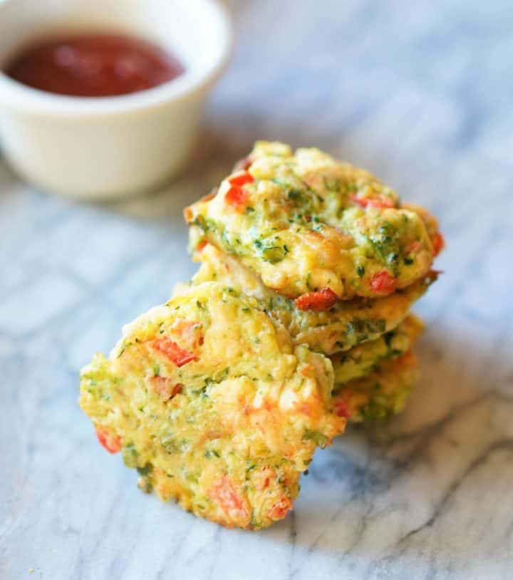 Stack of easy chicken vegetable patties on marble board and small bowl of ketchup in the back 