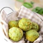 Basket of green spinach muffins on a gingham towel
