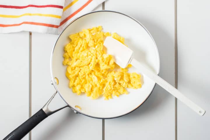 White pan with scrambled eggs and spatula 