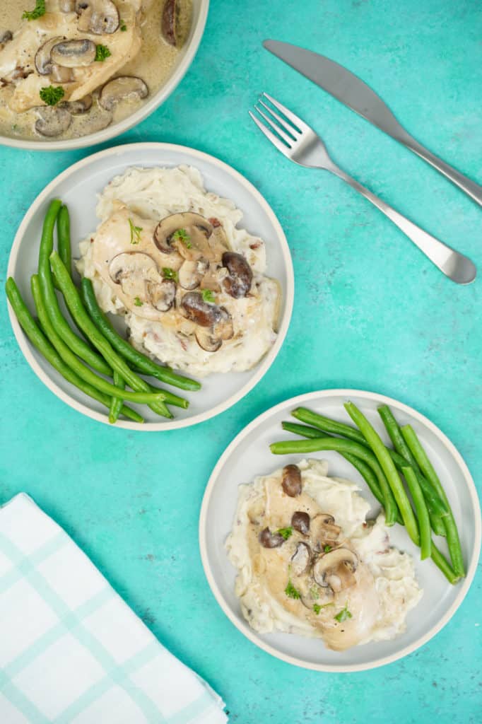 Several plates of mushroom chicken over mashed potato and green beans on the side