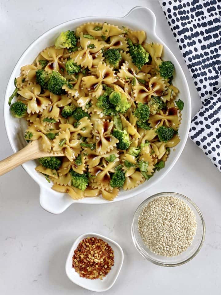 large bowl of asian bow pasta with toppings on the side 