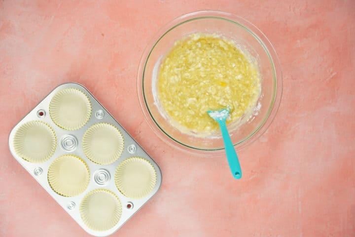 Muffin tin with liners, glass bowl with a glass bowl of batter