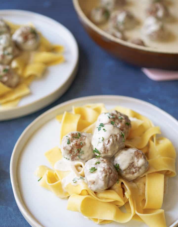 plated swedish meatballs on pappardelle pasta with pan in background