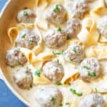 Pan of swedish meatballs in a creamy sauce with noodles and parsley for garnish