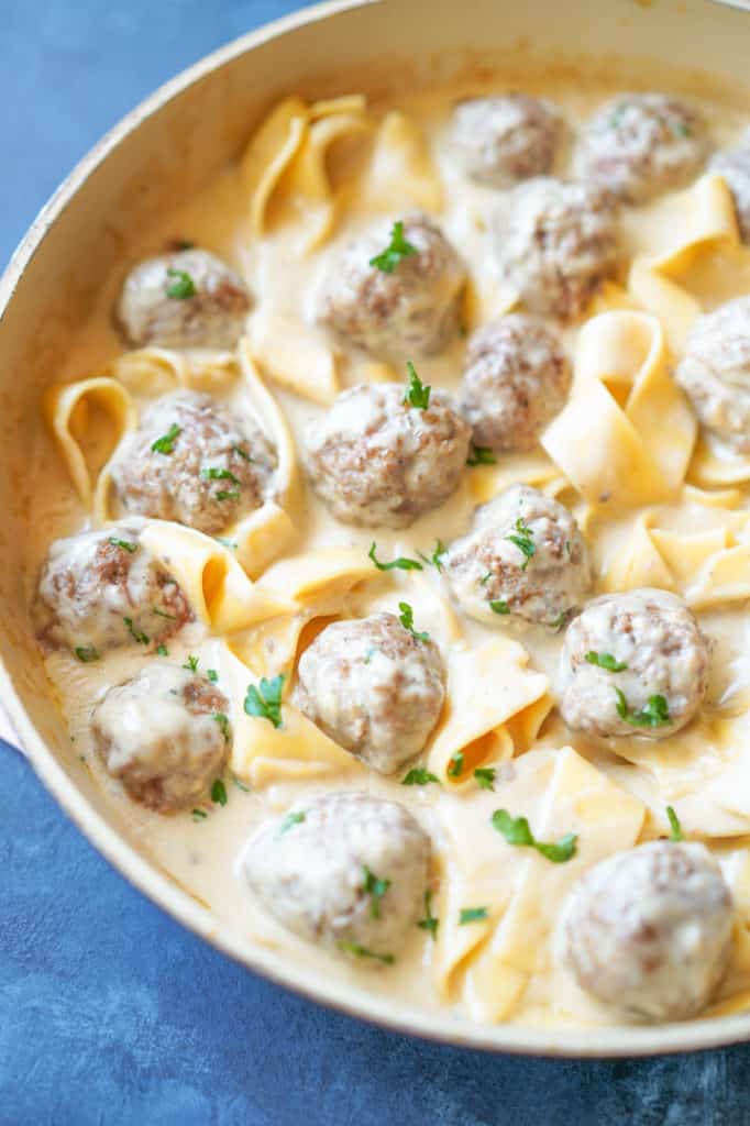 Pan of swedish meatballs in a creamy sauce with noodles and parsley for garnish