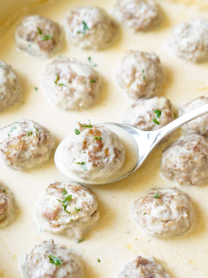 Close up of swedish meatballs on spoon in creamy sauce