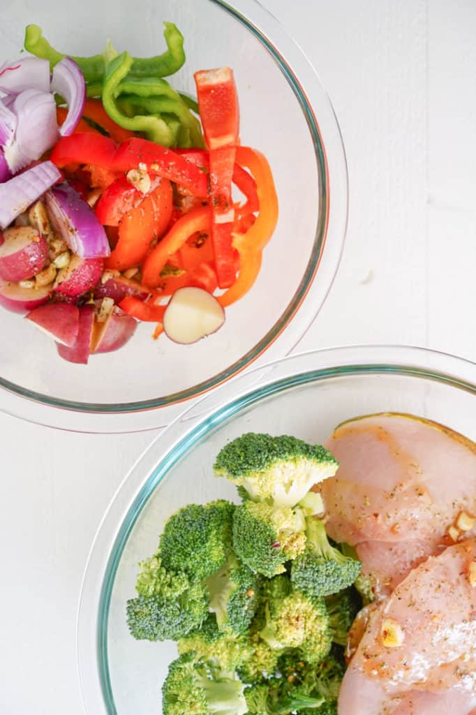 Two large glass bowls with sliced vegetables, another bowl with chicken and broccoli 