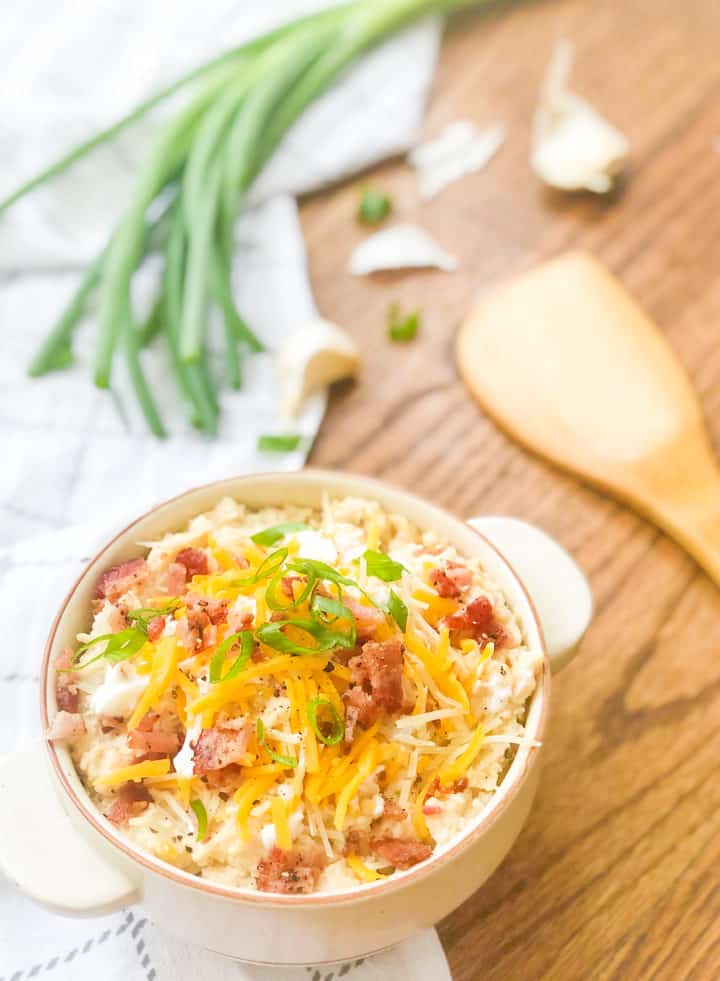 Cooked loaded mashed potatoes with toppings and green onions on the side