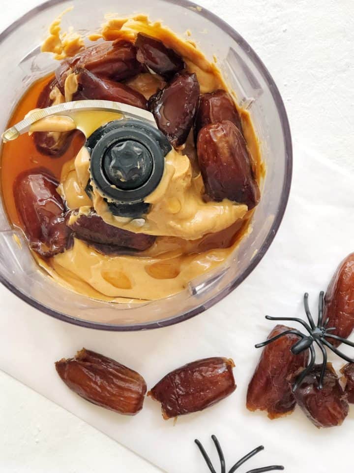 Top down image of peanut butter and dates being blended in a food processor 