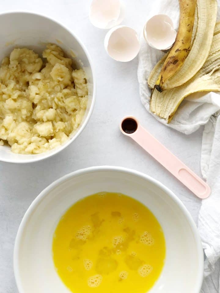 Overhead shot of mashed bananas and eggs and vanilla in measuring spoon 