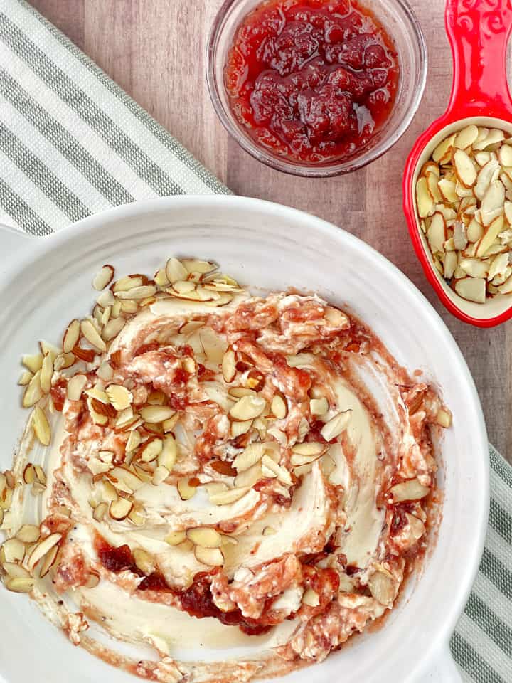 bowl of cranberry and cream cheese with cranberry on the side and almonds 
