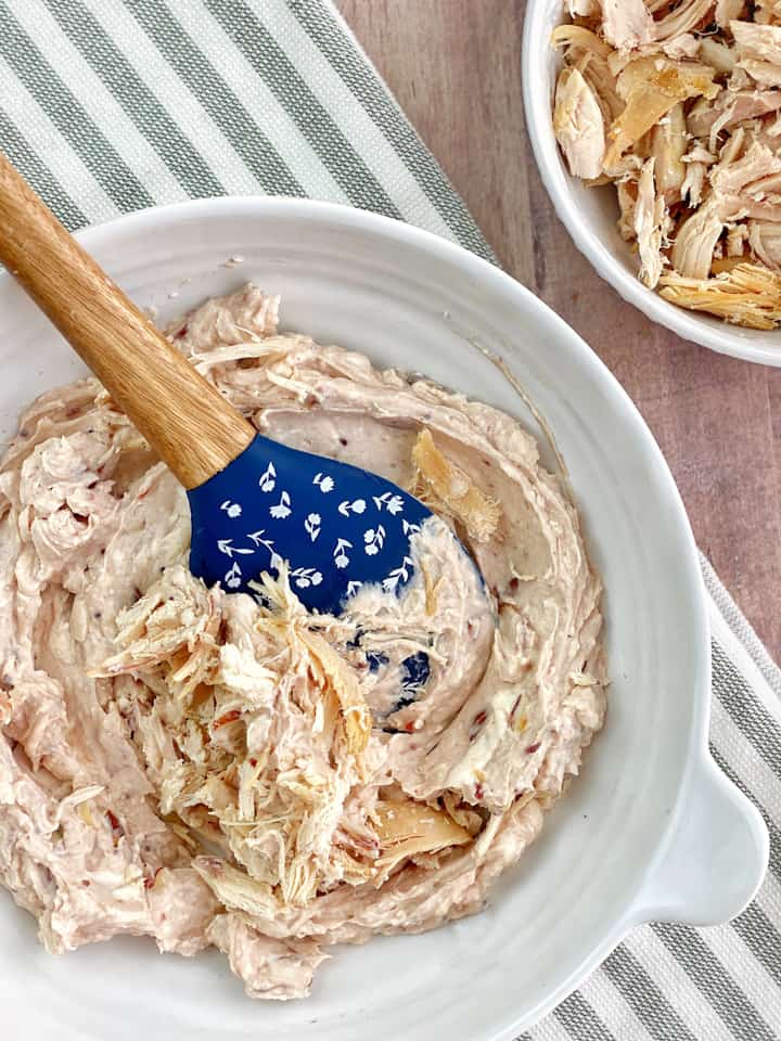 Mixing bowl with spatula that has cream cheese,shreded turkey, and cranberry 