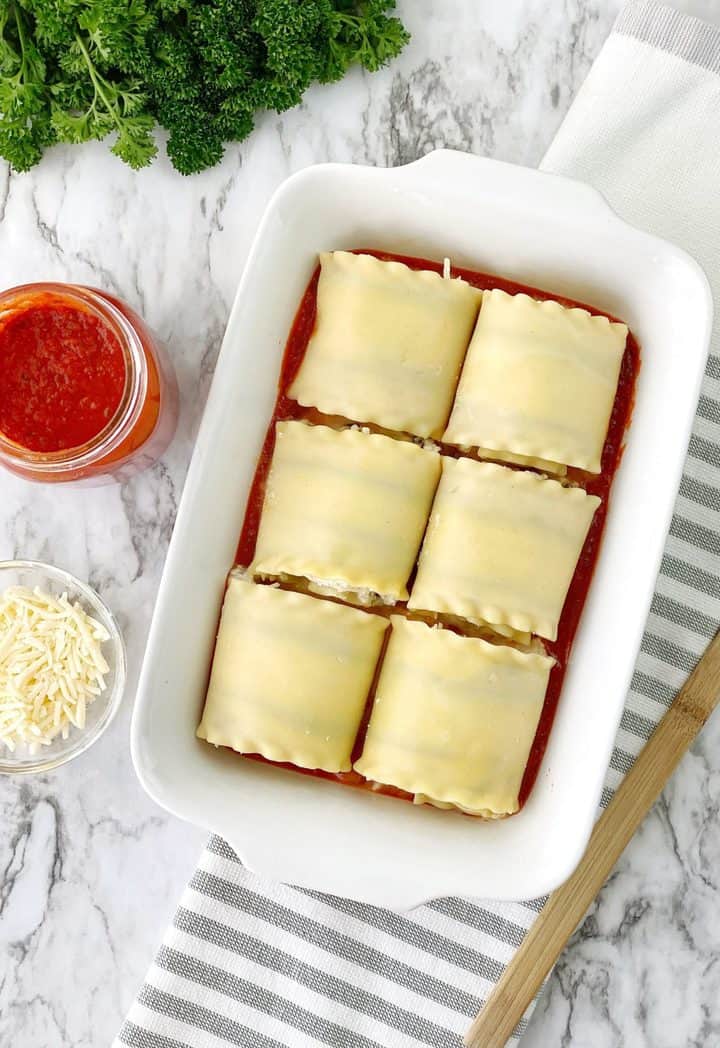 rolled up lasagna on a spread of pasta sauce 