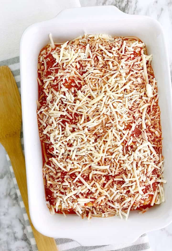 mozzerella on top of sauce and lasagna rolls 