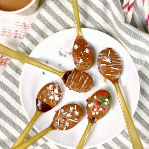 chocolate spoons on a plate with hot cocoa next to it on a striped napkin
