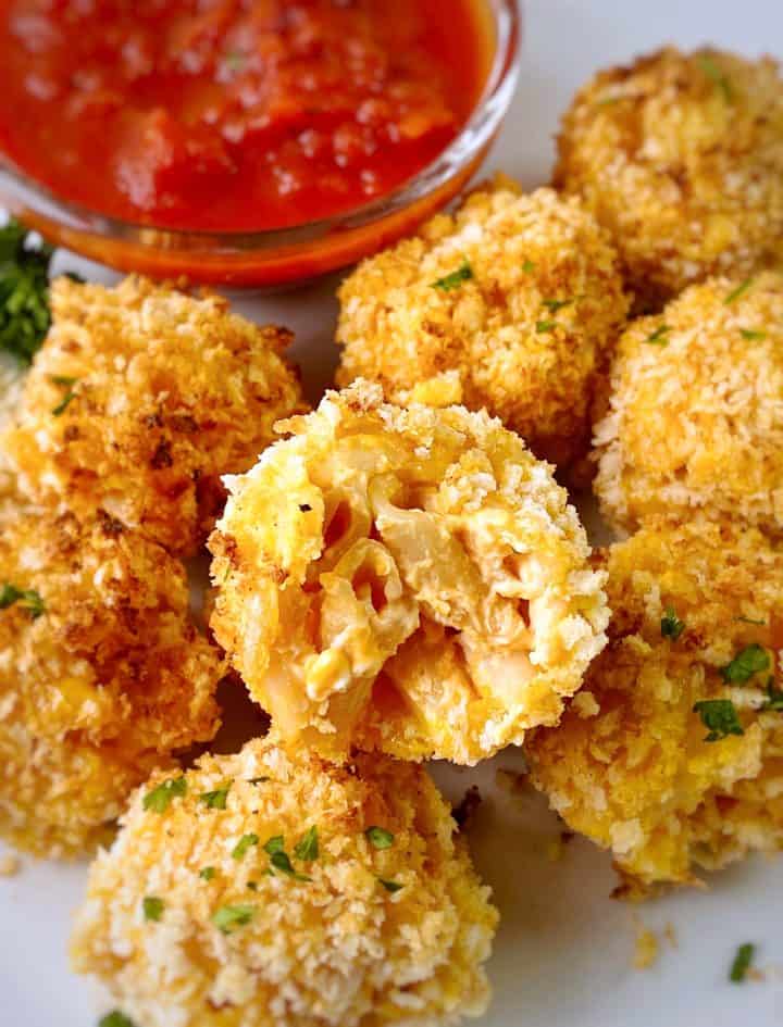 close up of mac and cheese balls with marinara on the side 