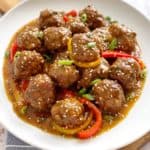 meatballs on a plate with scallions and bell pepper as garnish