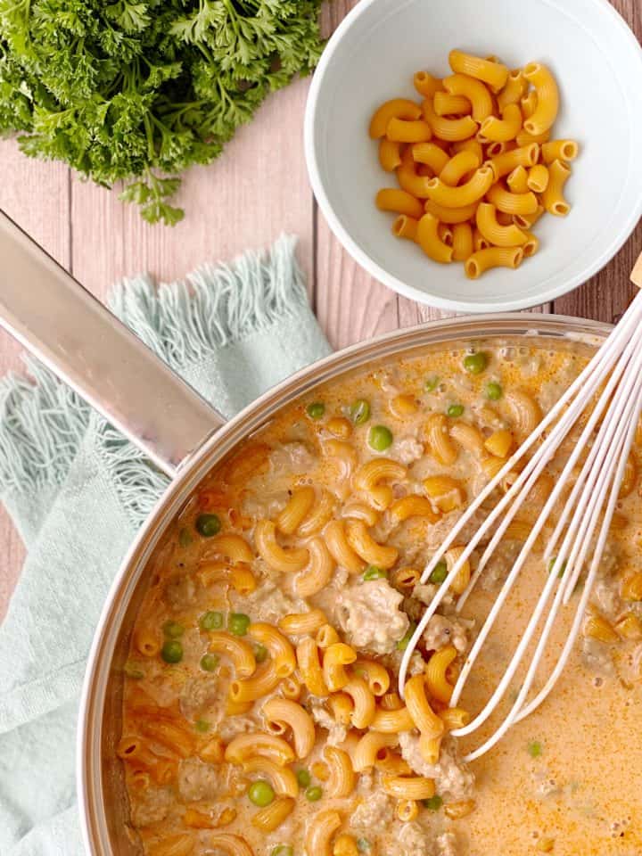 pan with mac and cheese, whisk on top and raw macaroni in a bowl for decor