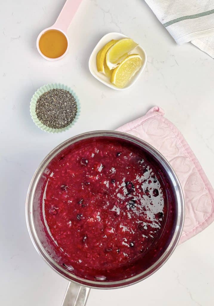 sauce pan with jam and lemon and honey on the side with chia seeds 