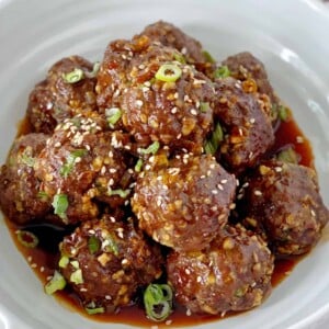 Meatballs in a bowl with sauce and garnish onions