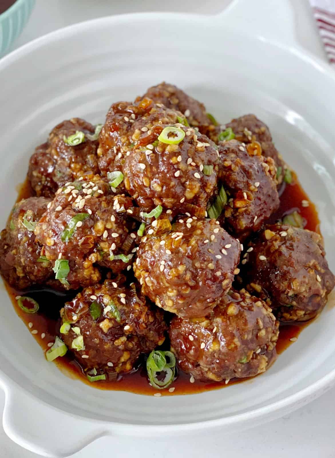 Meatballs in a bowl with sauce and garnish onions