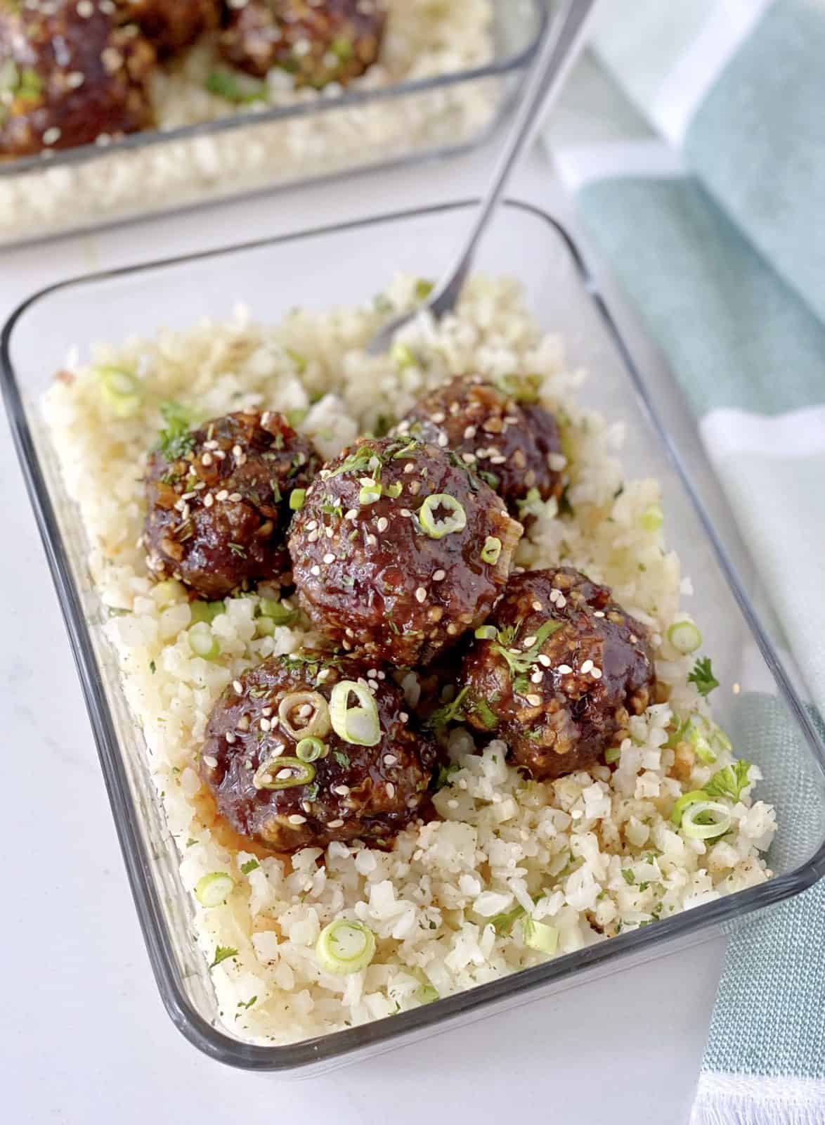meatballs with sauce on top of cauliflower rice 