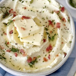bowl of mashed potatoes with butter and bacon and garnish on top