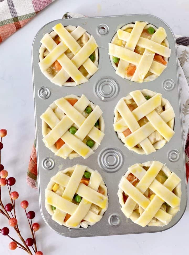 egg wash on top of mini pies in a tin