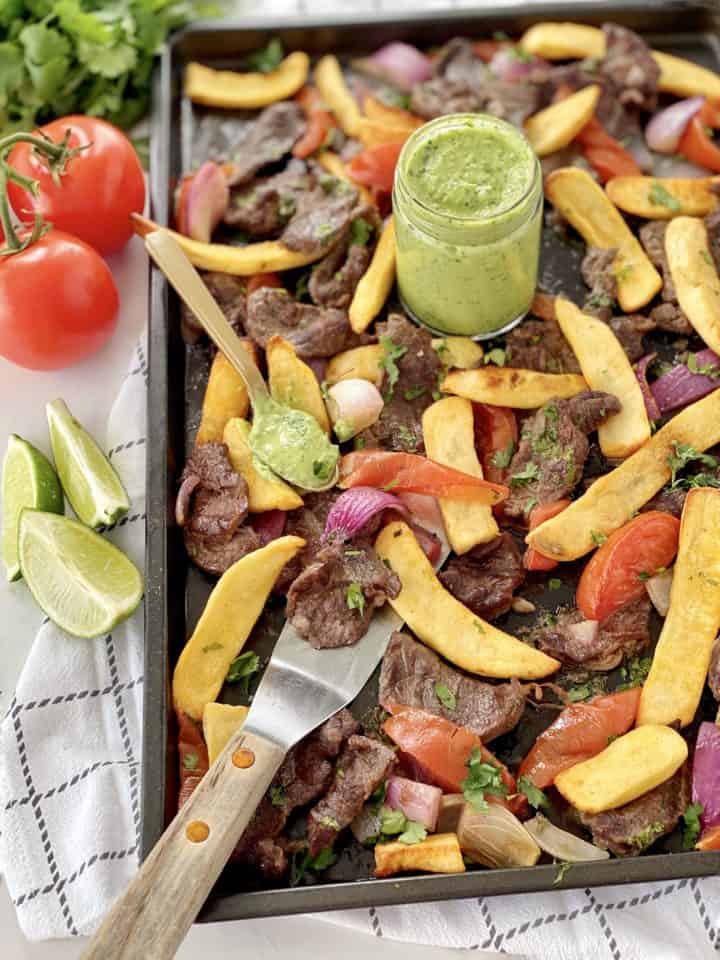 beef and fries and green sauce on a baking sheet 
