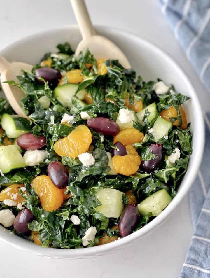 kale salad in a bowl with oranges and a spoon