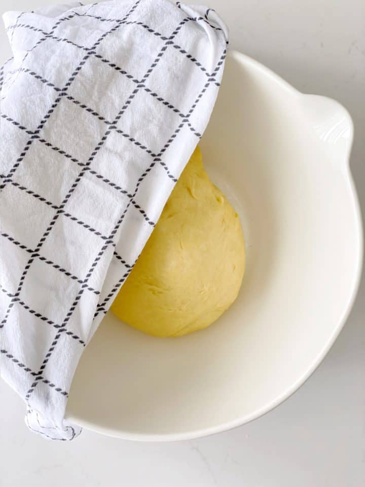 bowl with dough inside and a towel on top 