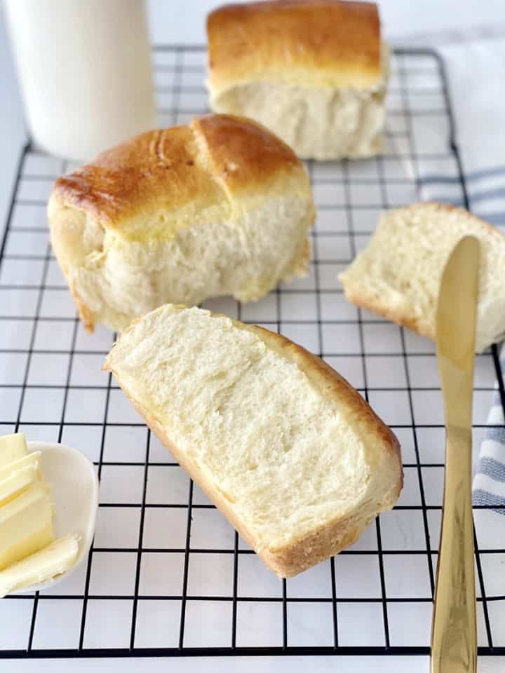 baked bread rolls on a wire rack with butter knife
