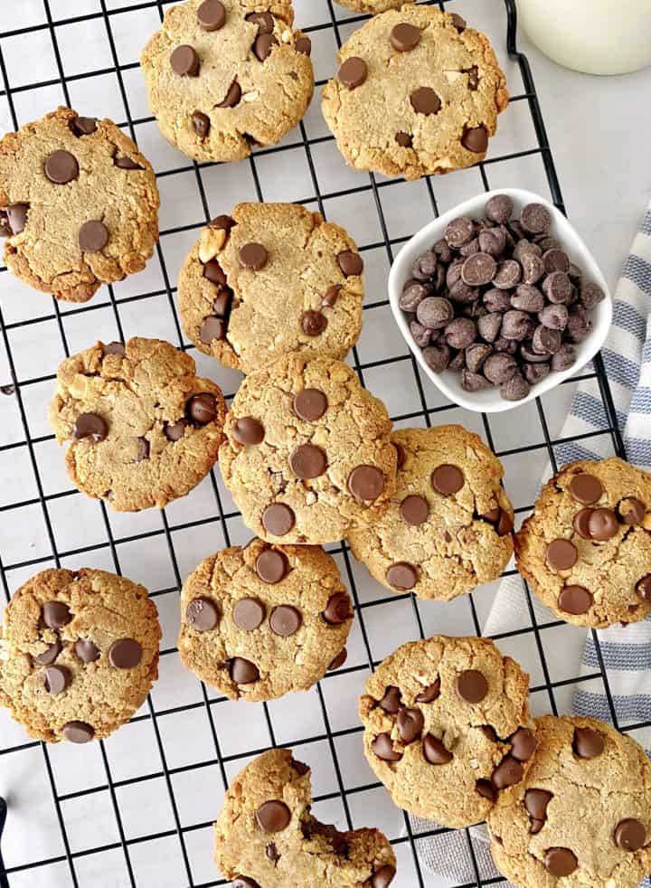 a bunch of chocolate chip cookies on a wire rack with chocolate chips in a bowl 