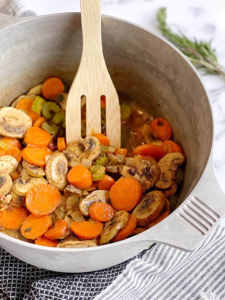 slotted spoon in carrots, mushrooms and celery pot 
