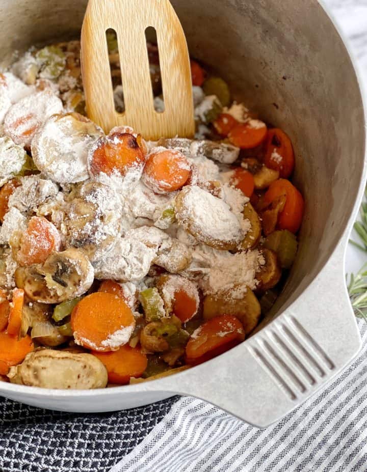 flour in vegetable mixture in a pot with a slotted spoon