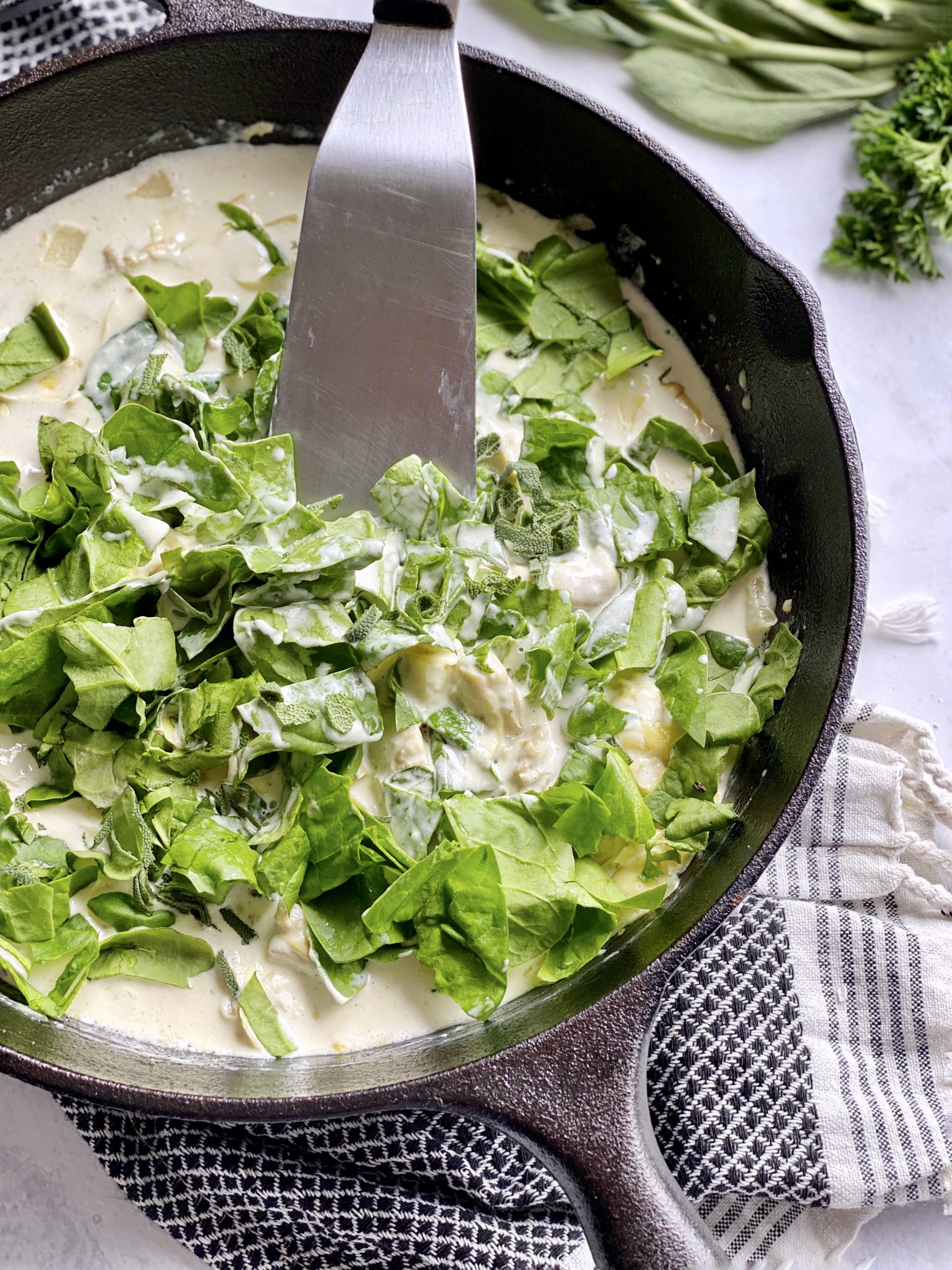 spinach and sage in cream sauce in a pan with a spatula 
