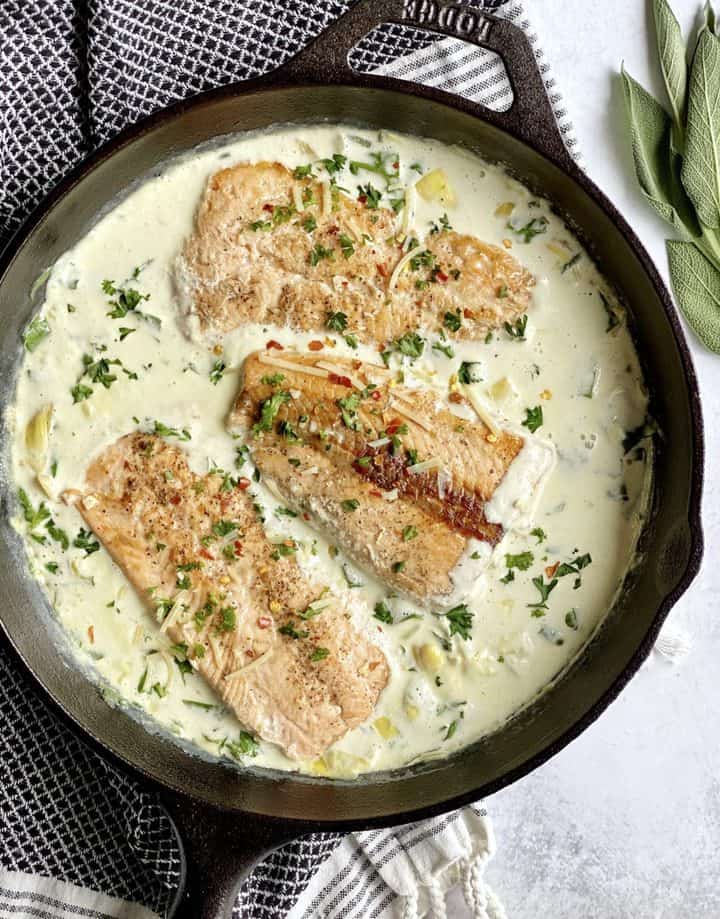 pan with cream sauce and salmon filets in a pan 
