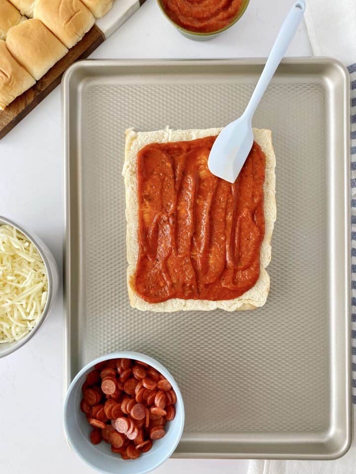 spatula over rolls with pizza sauce on top 
