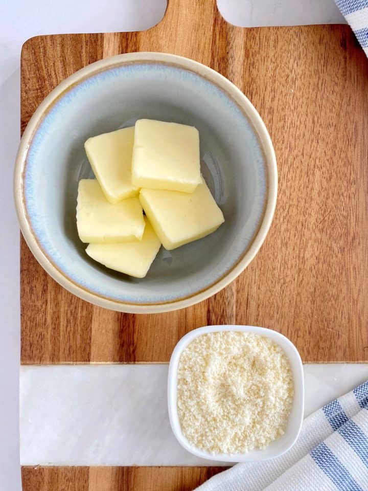 bowl of cut butter in a bowl next to a bowl of parmesan cheese 