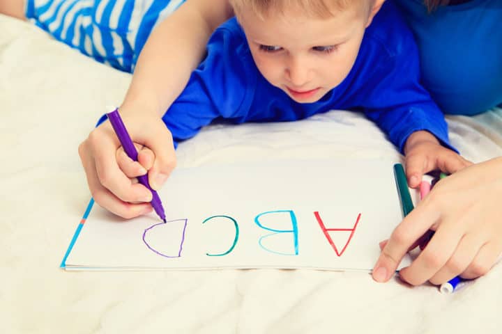 boy tracing letters with parent 