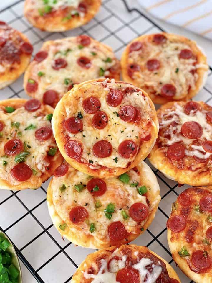 mini cauliflower pizzas stacked on a baking wire rack 